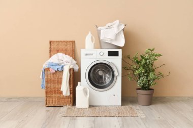 Çamaşır makinesi, deterjan ve sepetli çamaşır odasının içi.