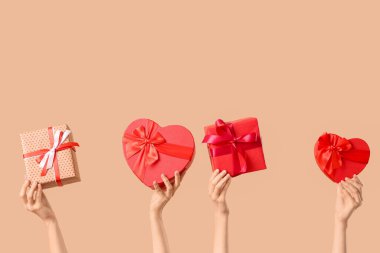 Bej arka planda farklı hediye kutularını tutan kadın elleri. Sevgililer Günü kutlaması