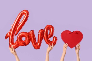 Balon şekilli kadın elleri aşk ve leylak arka planda kalp şeklinde bir kutu. Sevgililer Günü kutlaması