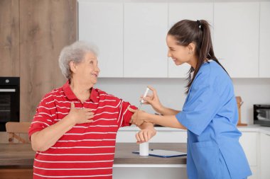 Doktoru olan diyabetik yaşlı bir kadın mutfakta tükenmez kalem kullanıyor.