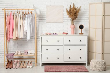 Modern giyinme odasının şık iç mekanı kadın kıyafetleri ve otlarla dolu.