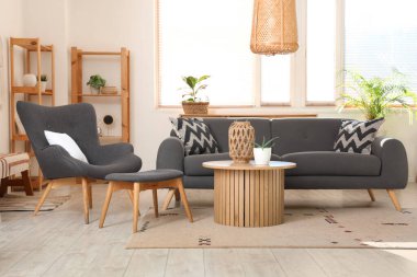 Şık bir oturma odası, rahat gri koltuğu, kanepesi ve ahşap kahve masası var.