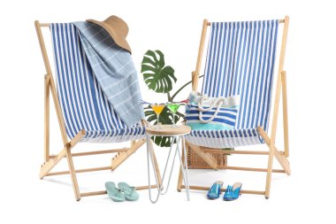 Plaj aksesuarlı çizgili iskemleler ve beyaz arka planda izole edilmiş kokteyl bardaklarıyla dolu bir masa.