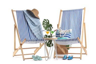 Plaj aksesuarlı çizgili iskemleler ve beyaz arka planda izole edilmiş kokteyl bardaklarıyla dolu bir masa.