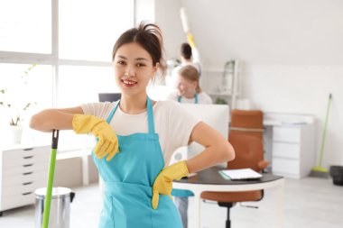 Ofisinde paspas olan Asyalı kadın hademe.