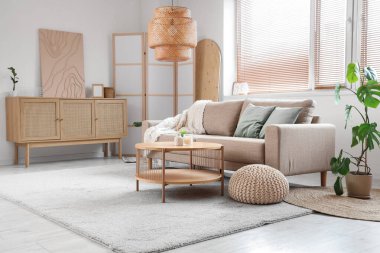 Oturma odasının içinde kanepe, masa, çekmeceler ve katlanır ekran var.