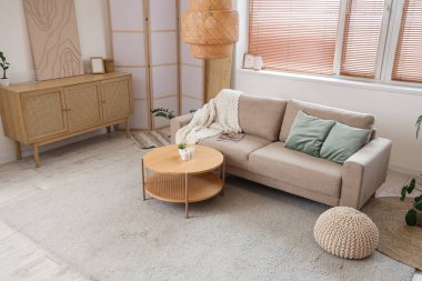 Oturma odasının içinde kanepe, masa, çekmeceler ve katlanır ekran var.