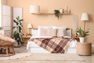 Yatak odası, yatak odası, katlanan ekran ve bej duvarın yanındaki bitkiler.