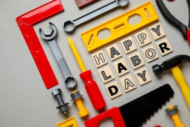 Oyuncak inşaat aletleri ve kelimeler gri arka planda mutlu LABOR Günü. İşçi Bayramı kutlamaları