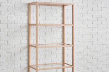 Beyaz tuğla duvarın yanındaki boş ahşap kitaplık