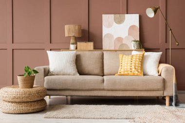 Rahat kanepe, puf ve zemin lambaları oturma odasının içindeki kahverengi duvarın yanında, yakın plan.