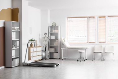 Koltuğu, sandalyeleri ve iskeleti olan bir fizyoterapist ofisi.