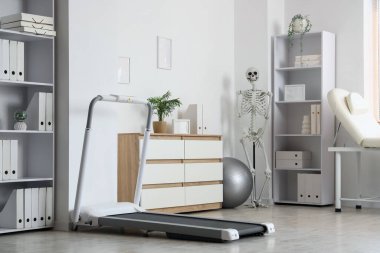 Raf üniteleri, koşu bandı ve insan iskeleti olan fizyoterapist ofisi.