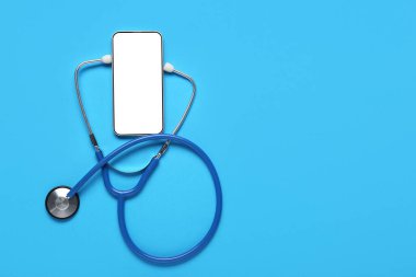 Mavi arka planda steteskoplu boş bir cep telefonu.