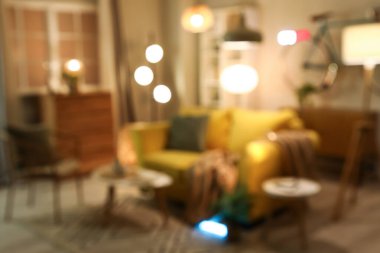 Bulanık oturma odası, sarı kanepe, koltuk ve akşam lambaları.