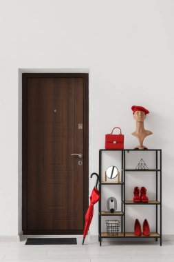 Koridorun içinde kapısı, raf ünitesi ve şemsiyesi var.