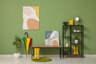 Koridorun içinde bank, raf ünitesi ve çizme var.