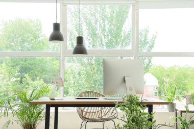 Ofiste pencerenin yanında bilgisayar ve lambalar olan işyeri