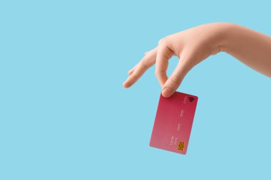 Mavi arka planda kredi kartı olan bir kadın.