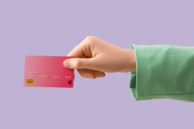 Leylak arka planında kredi kartı olan bir kadın.