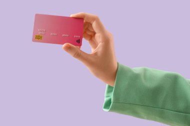 Leylak arka planında kredi kartı olan bir kadın, yakın plan.