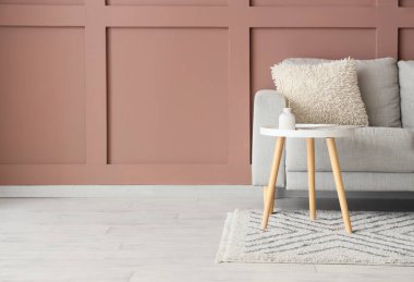 Rahat gri kanepe ve kahverengi duvarın yanındaki masa oturma odasının içinde, yakın plan.