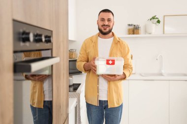 Mutfakta ilk yardım çantası olan genç bir adam.