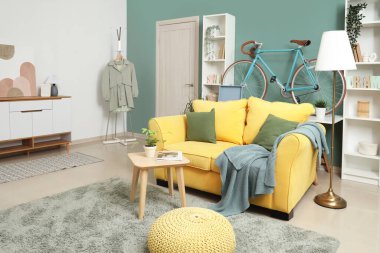 Bisikletli, sarı kanepeli ve raf üniteli şık bir oturma odası.