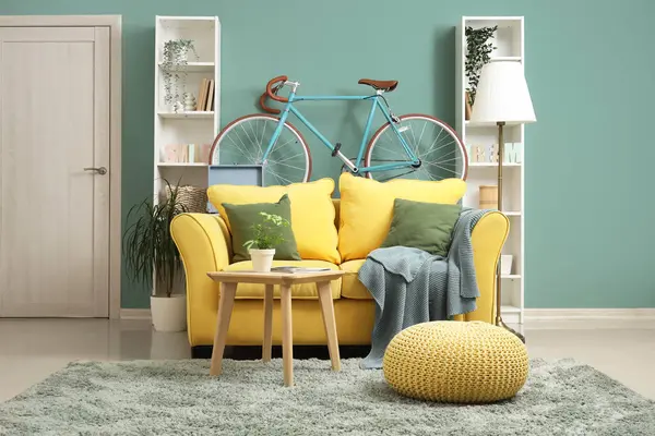Bisikletli, sarı kanepeli ve raf üniteli şık bir oturma odası.
