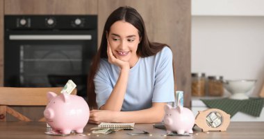 Kumbaralı ve mutfaktaki masada parası olan mutlu bir kadın.