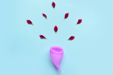 Mavi arka planda regl fincanı ve çiçek yapraklarıyla kompozisyon