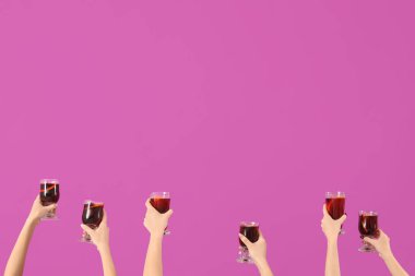 Pembe arka planda sıcak şarap kadehleriyle kadın elleri.