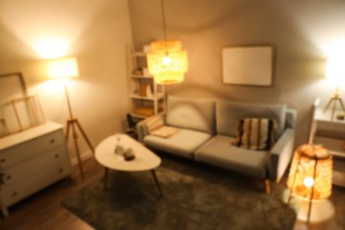 Gri kanepeli, kahve masalı ve akşamları parlayan lambalı modern oturma odasının bulanık manzarası.