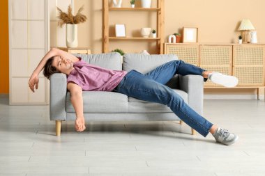 Yorgun genç adam evdeki kanepede yatıyor.