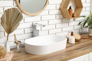 Banyodaki beyaz tuğla duvarın yanındaki çekmecelere lavabo ve banyo malzemeleri.