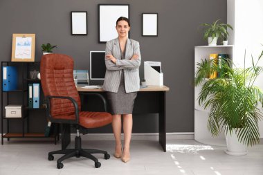 Şık bir ofiste, koltuğun yanında ve işyerinde çalışan kadın bir ofis çalışanı.