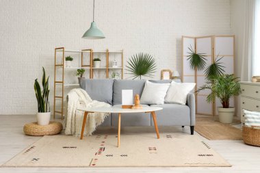 Oturma odasının içinde kanepe, katlanan perde ve bitkiler var.