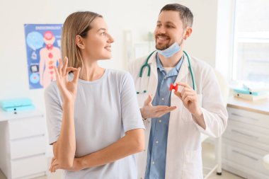 Tiroid bezi modeli olan bir erkek endokrinolog ve klinikte durumu iyi olan genç bir kadın.