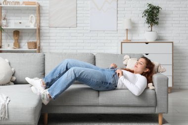 Dar kotlu şişman kadın evdeki kanepede uzanıyor. Aşırı ağırlık kavramı