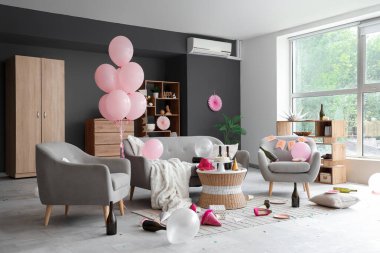 Doğum gününden sonra kanepe, koltuk ve masa ile dağınık oturma odasının içinde.