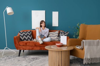 evde koltukta oturan genç ve güzel kadın