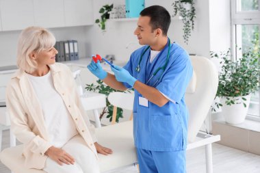 Tiroid bezi modelini klinikteki kadın hastaya gösteren erkek endokrinolog.