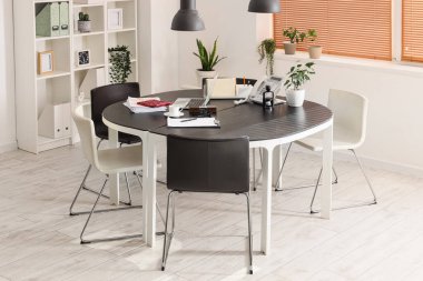 Masası, raf ünitesi ve bitkileri olan ışık ofisinin içinde.