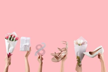 Pembe arka planda ayakkabılı, çiçekli ve hediye kutulu kartpostal tutan bir kadın. Uluslararası Kadınlar Günü için Alışveriş