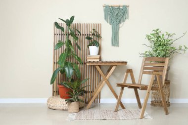 Oturma odasının içinde yeşil bitkiler, tahta sandalye ve masa var.