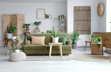 Yeşil çiçekli ve kanepeli aydınlık oturma odasının içi.