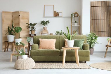 Yeşil çiçekli ve kanepeli aydınlık oturma odasının içi.