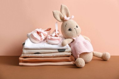 Bej arka planda bebek kıyafetleri ve oyuncak yığını