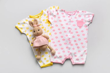 Beyaz arka planda oyuncak tavşanı olan bebek kıyafetleri.