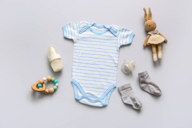 Hafif arka planda oyuncakları ve aksesuarları olan bebek kıyafeti.
